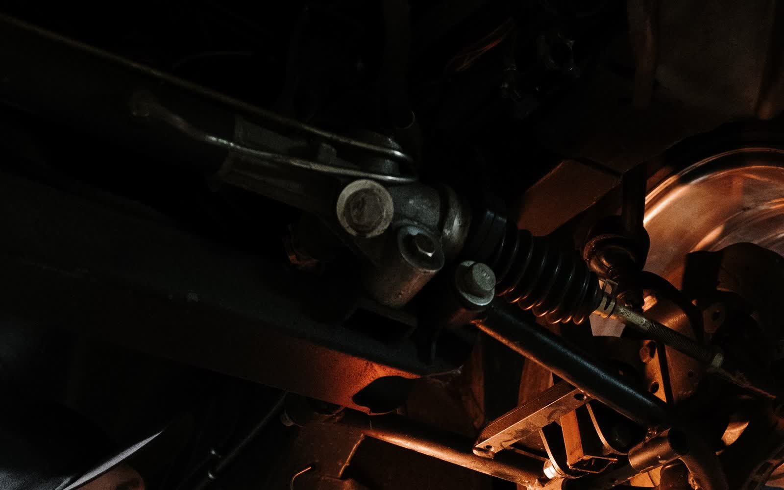 MOT tester inspecting a car's steering and suspension with an inspection lamp