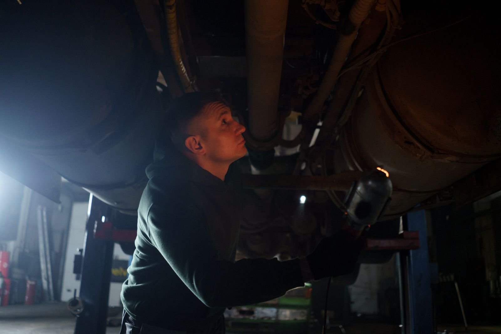 Mechanic inspecting the underside and exhaust of a car during an MOT test