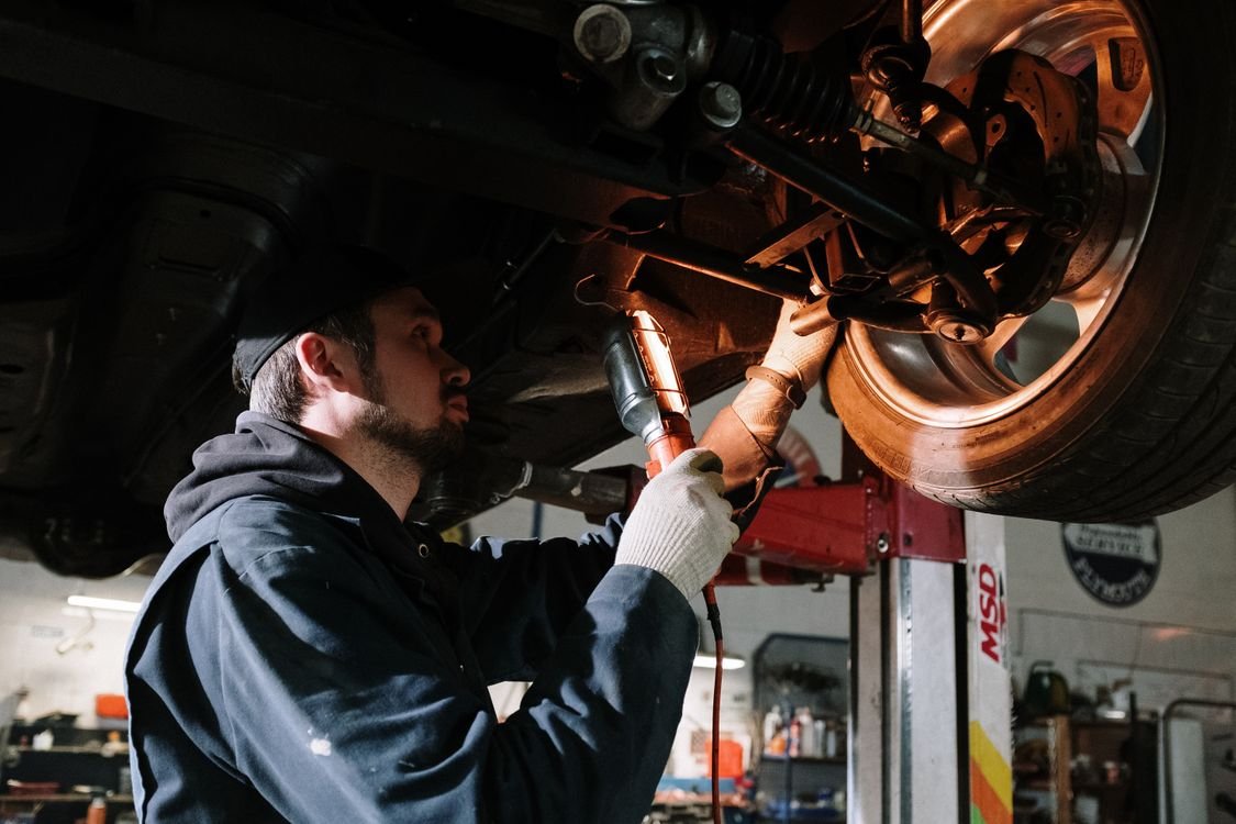 Tester examining suspension and brakes with an inspection lamp