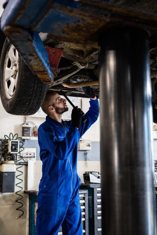 Mechanic checking a car's undercarriage during an MOT test